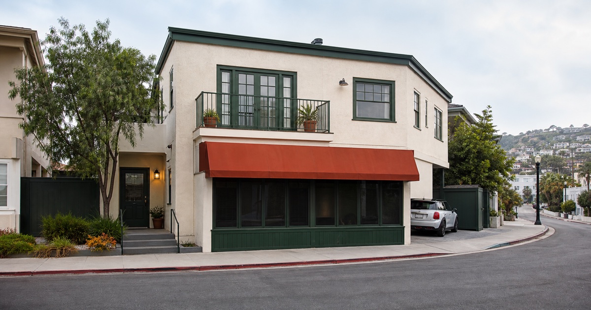 Modest Laguna Beach mixed-use lodging property with a blank awning and organized off-street parking.