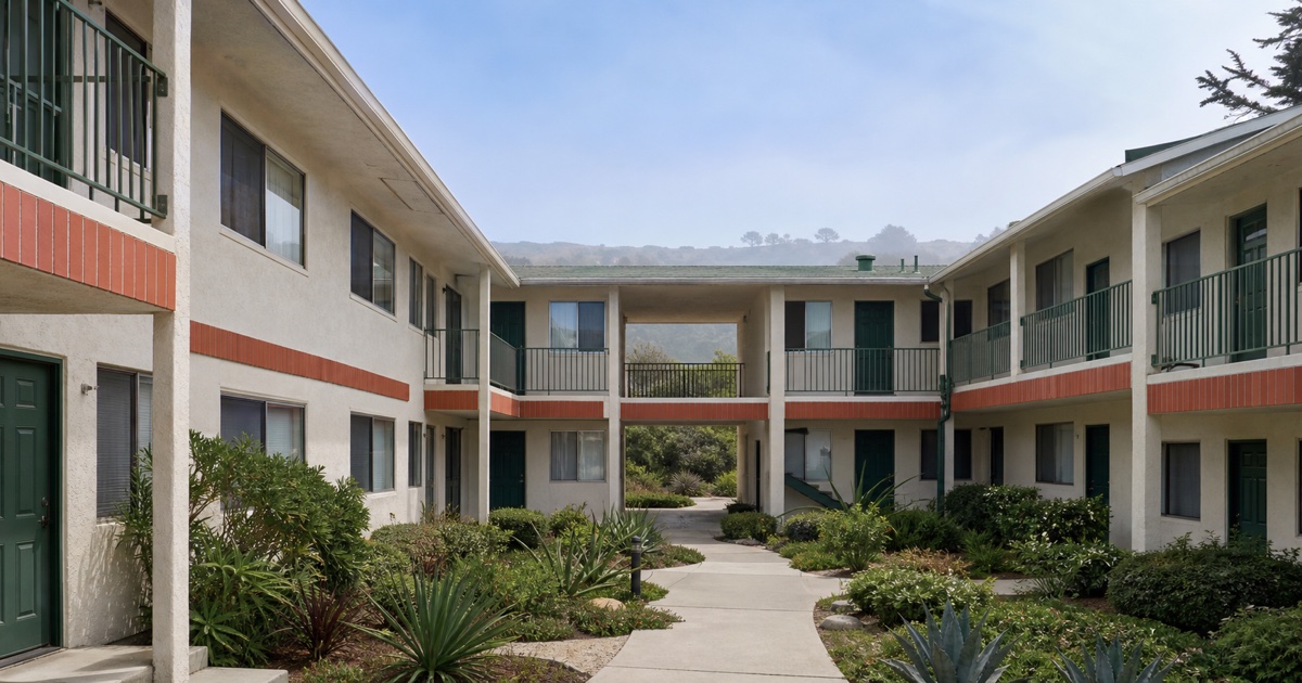 Open-air Carlsbad apartment courtyard with visible entries, windows, balconies, and breezeways.
