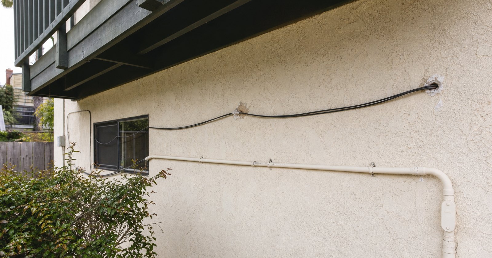 Unapproved cable route and small wall penetrations on a rental-property exterior
