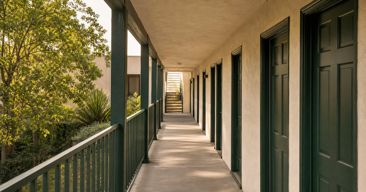 Long California apartment corridor leading from occupied entries toward a bright exit
