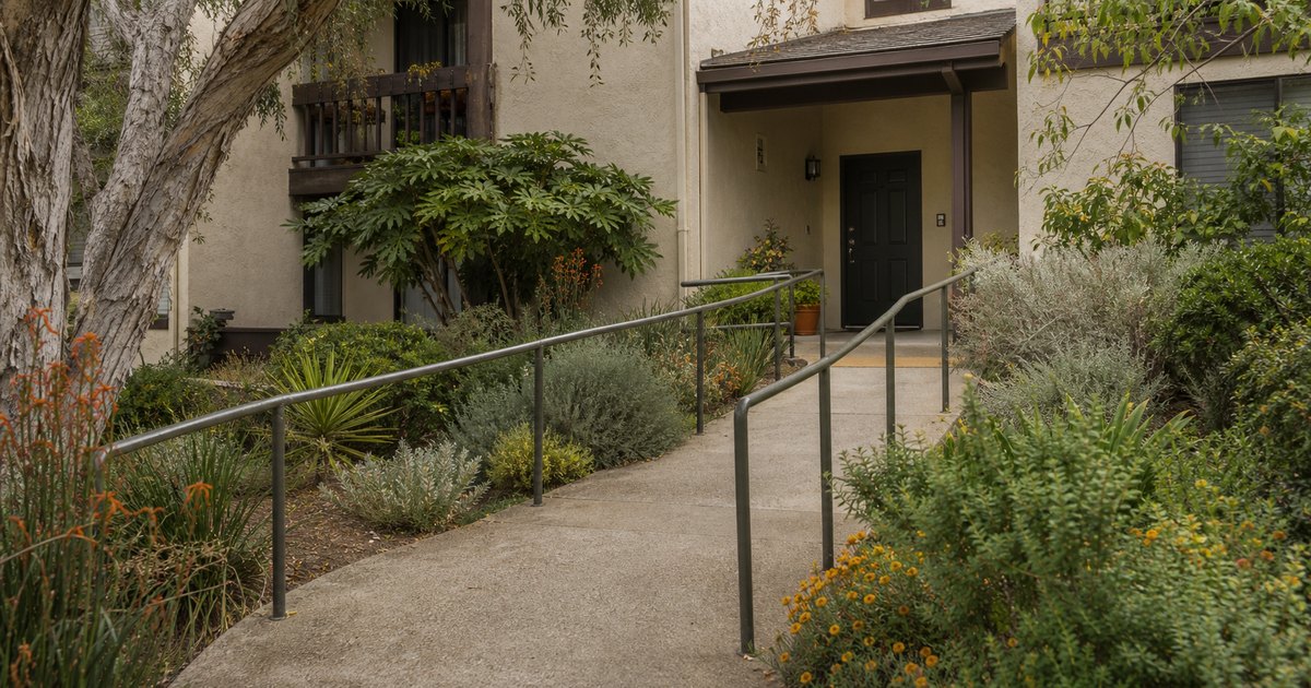 California apartment entrance reached by a gently sloped path with handrails and a level threshold