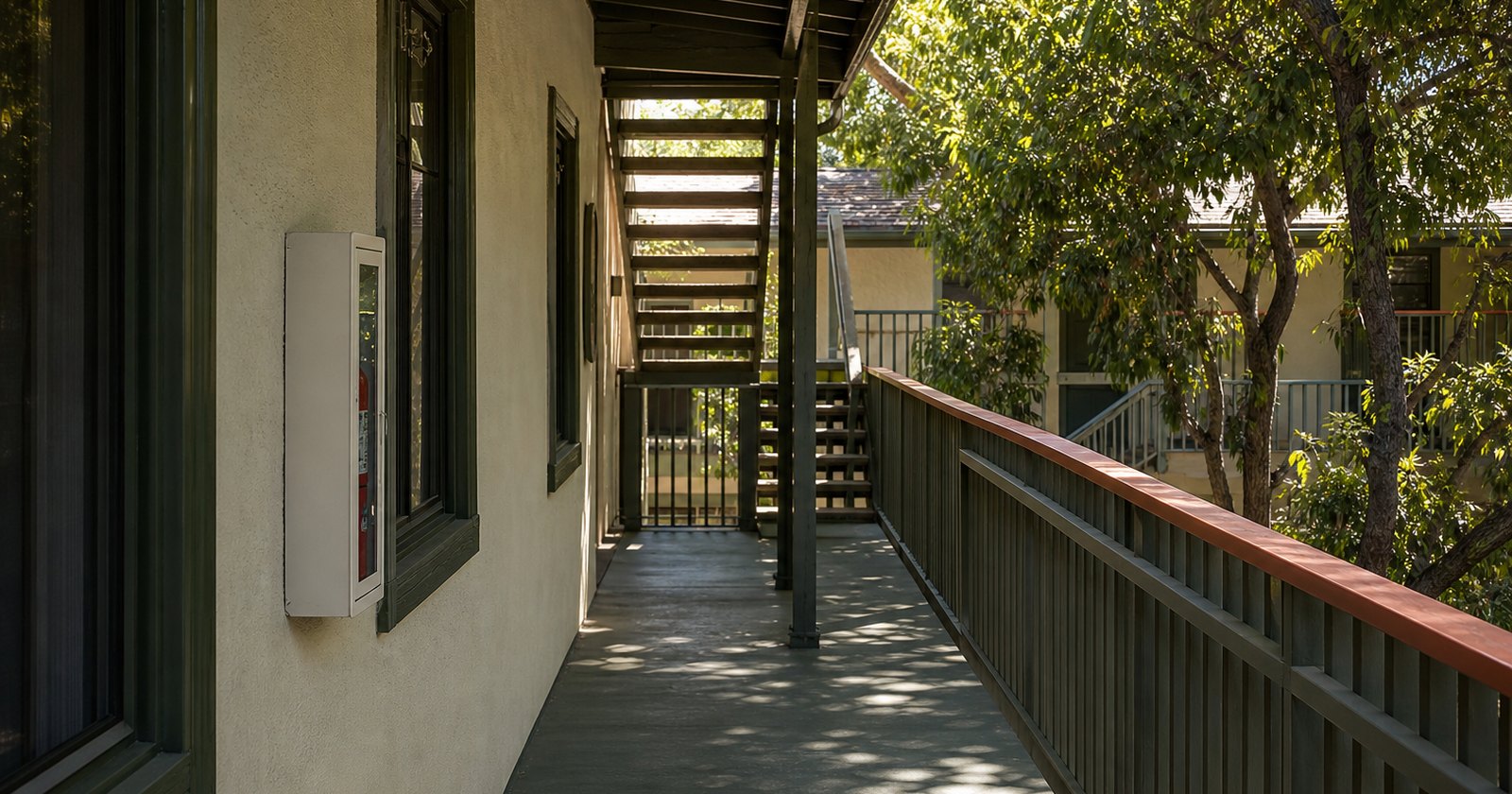Clear exterior egress path beside an unmarked fire-extinguisher cabinet at a rental building