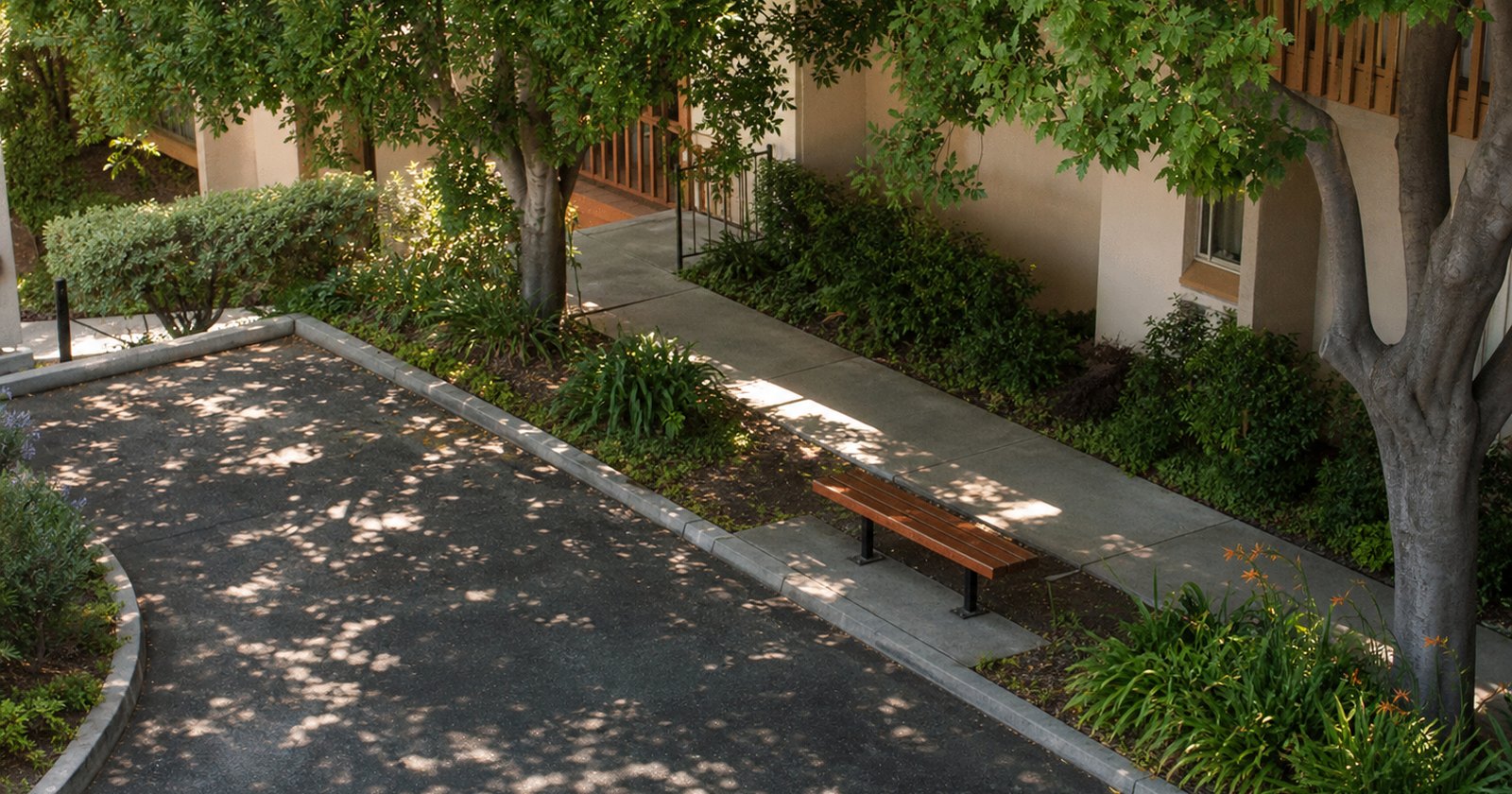 Generously spaced parking bay directly beside a shaded apartment walkway and bench
